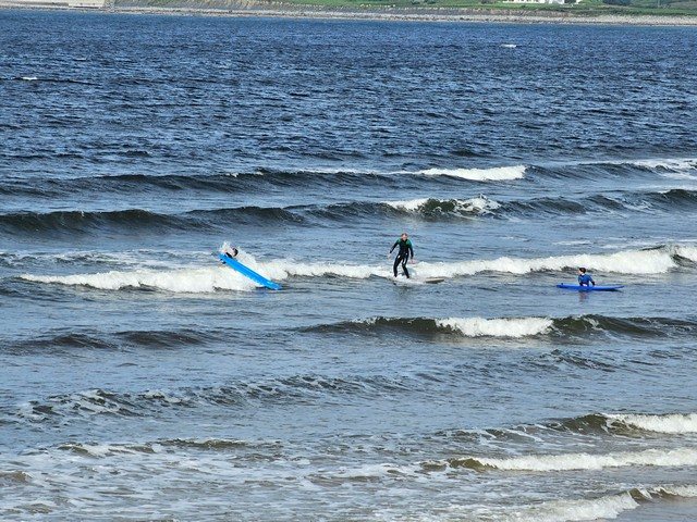 Surfer finishing a knee high wave in the shallows with plenty more surfers in the water